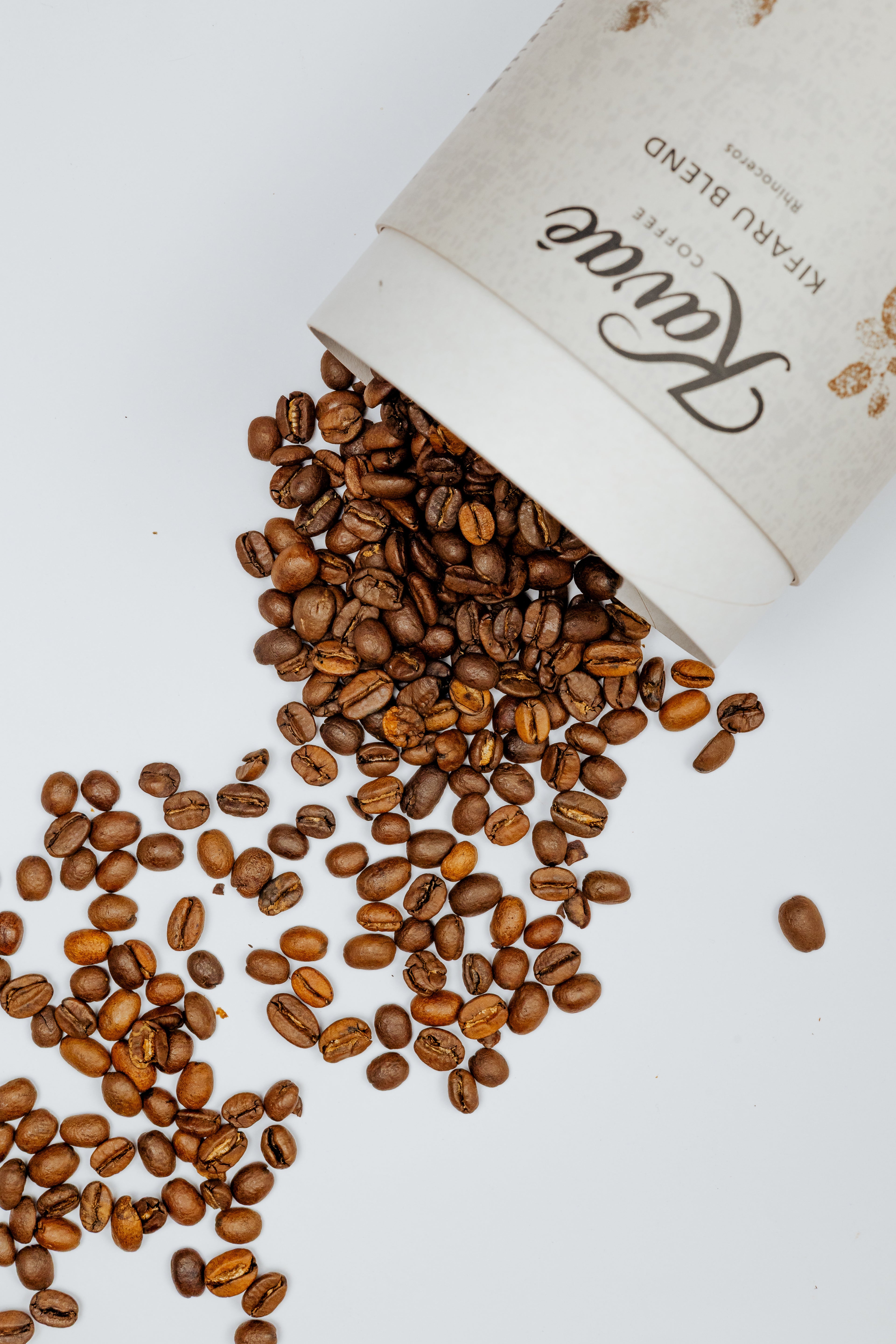 Open coffee bag spilling out coffee beans on a white surface