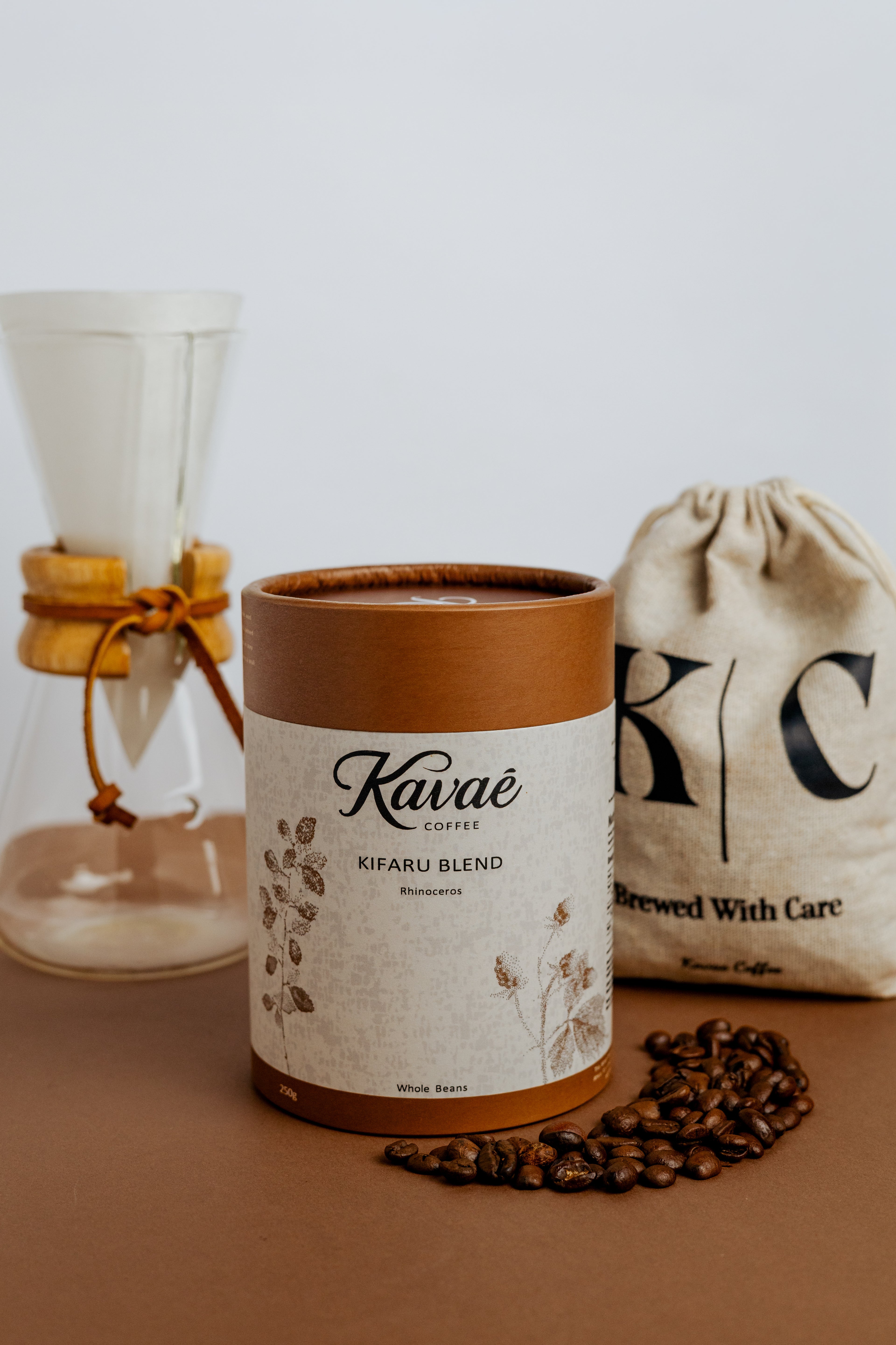 Kuvae coffee canister with coffee beans and a coffee bag on a wooden surface.
